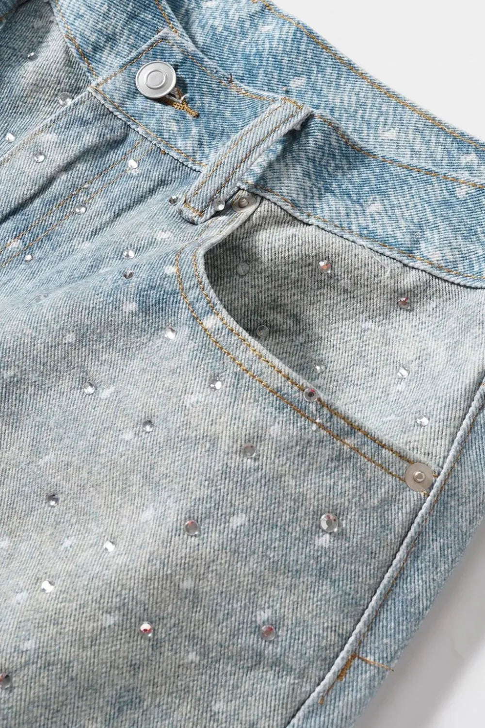 Close up detail of rhinestone pockets on men's denim Bermuda shorts blue wash
